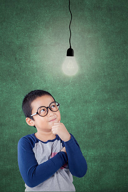 istock Male child looking at light bulb in class 598141956