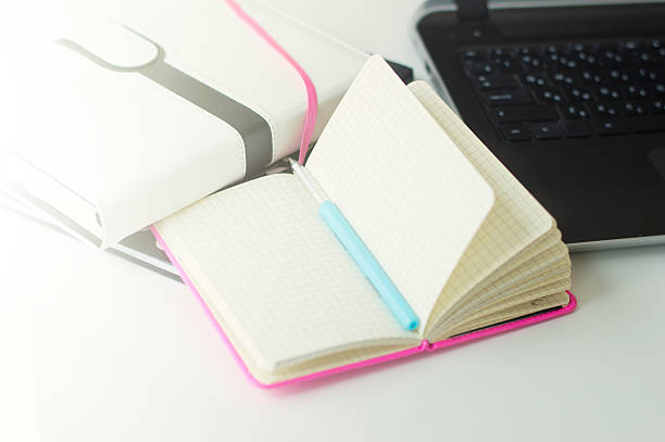 istock Paper notebooks, pen and black laptop on white office table 598148098
