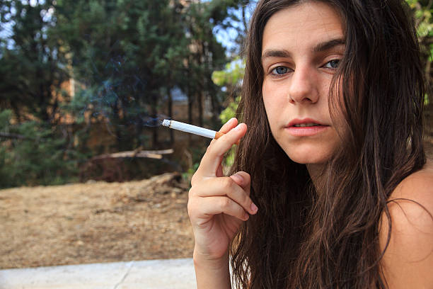 White caucasian girl , very pretty and blue eyes smoking a cigar in a pool in summer.