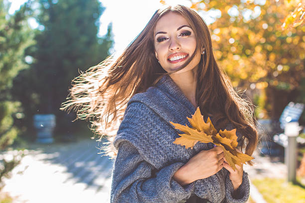 hübsche frau im park mit herbstlichen gelben blättern - damen top gold stock-fotos und bilder