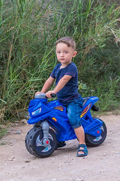 Little baby boy riding on the blue motobike