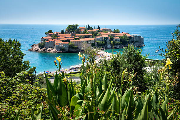Sveti Stefan, Budva, Montenegro Island of St Stefan in Budva, Montenegro on a clear sunny day. Flowers are visible in the front view. budva stock pictures, royalty-free photos & images