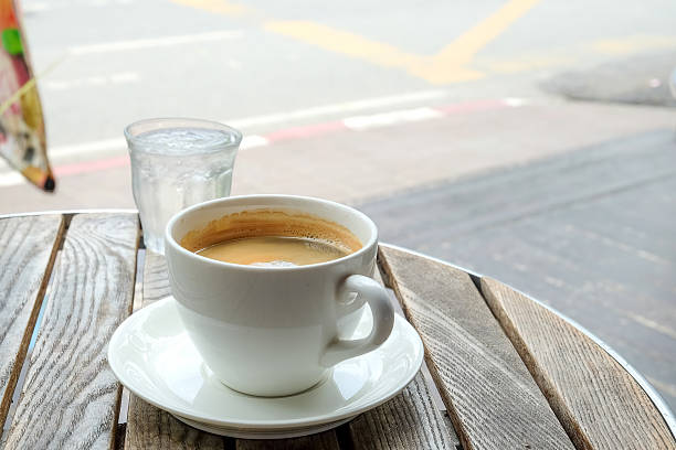 White coffee cup and glass water on wooden table.