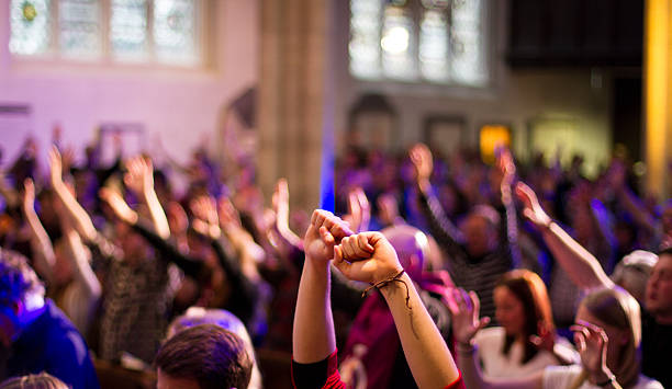 Worshippers raise their hands at a Christian church service York, United Kingdom - May 15, 2016: A congregation worship with raised hands at a Christian church service held at St Michael Le Belfry. sing praise stock pictures, royalty-free photos & images