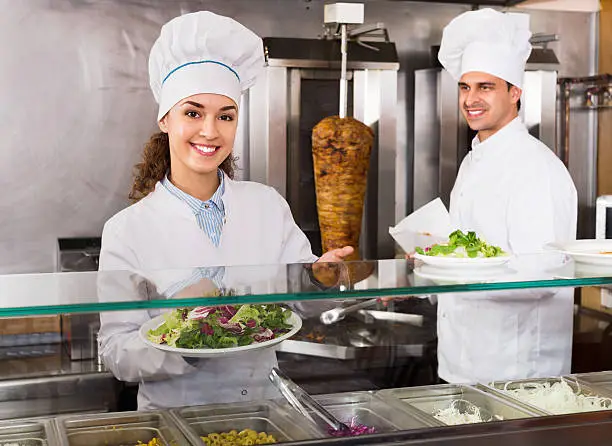 Photo of Portrait of two hospitable chefs with kebab at fastfood place