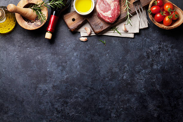 Raw beef steak cooking Raw beef steak cooking and ingredients. Meat piece, red wine, herbs and spices. Top view with copy space over stone table slate rock photos stock pictures, royalty-free photos & images