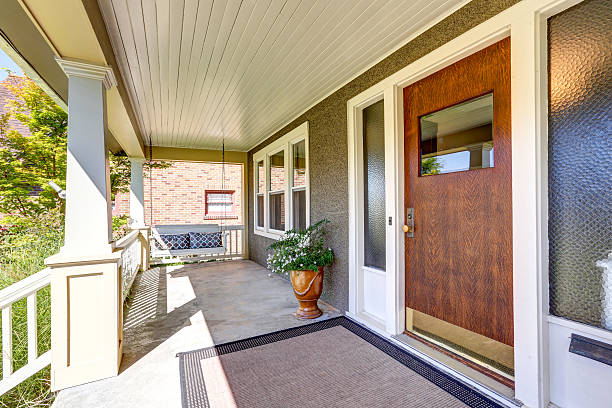 istock Front covered porch with hanging swing and flower pot . 598165516