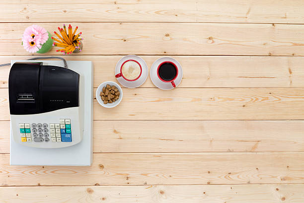 dos tazas de café negro junto a una caja registradora - cash register register wealth checkout counter fotografías e imágenes de stock