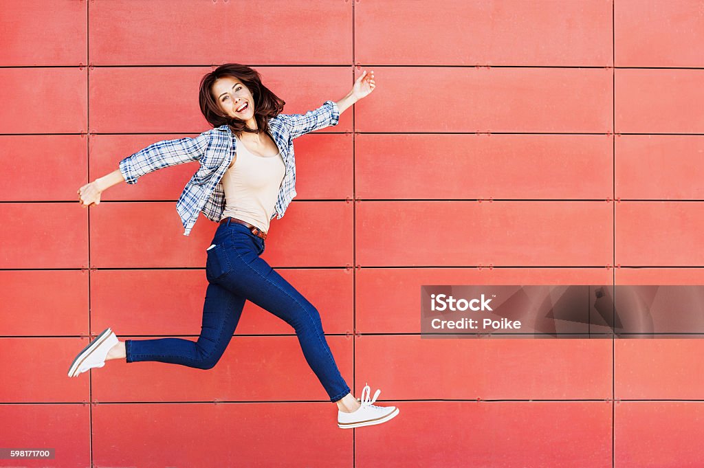 Jumping happy girl Excited girl is jumping against a red wall Jumping Stock Photo