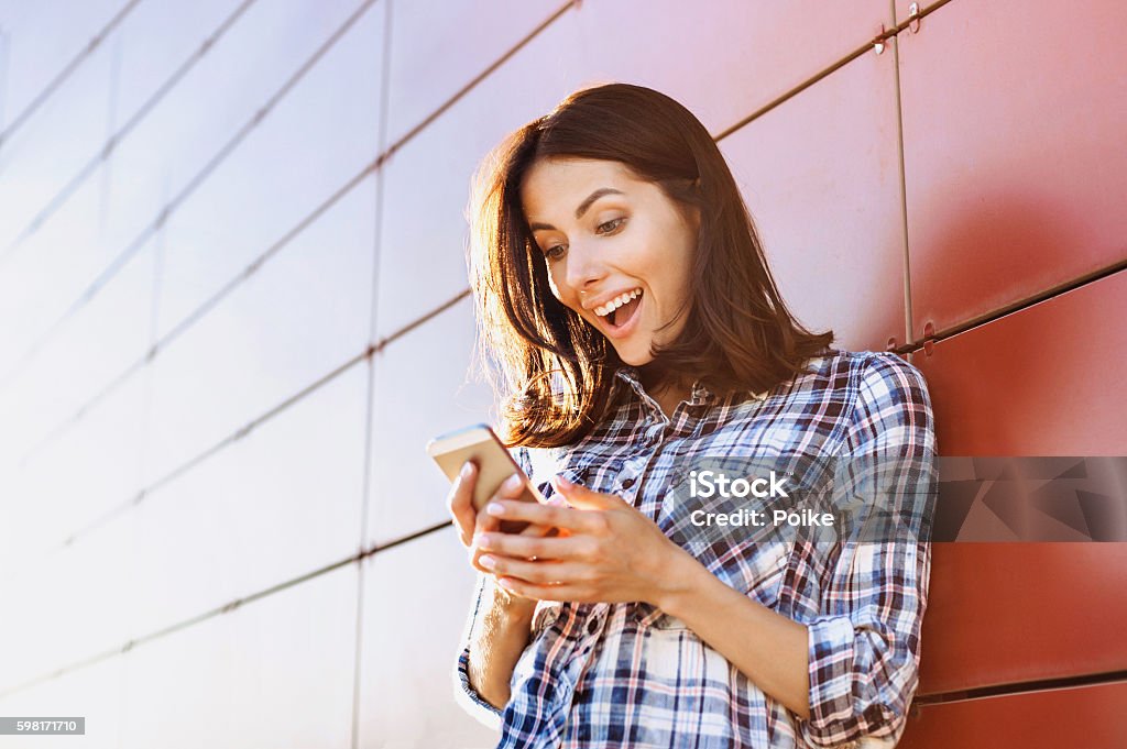 Surprised girl using smart phone Happy young woman using smart phone Mobile Phone Stock Photo