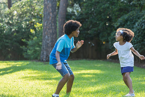 istock Mixed race brother and sister playing in park 598178846
