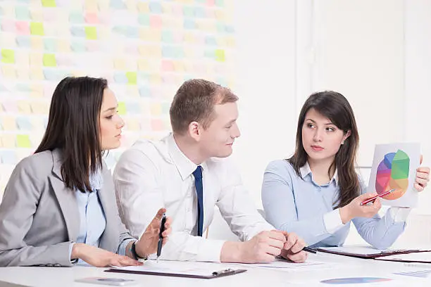 Woman attracting attention of her business partners by point data on a pie chart