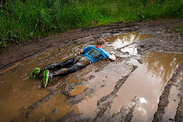 Runner Athlete fall down to the dirty puddle in the rural road athlete fails stock pictures, royalty-free photos & images