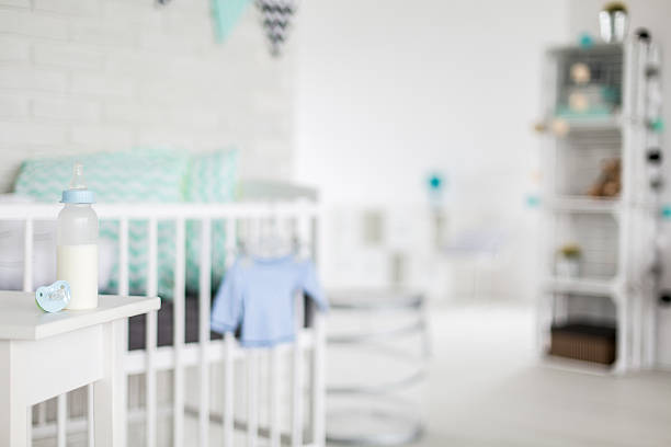 Baby bottle and pacifier in a blurred bright baby room