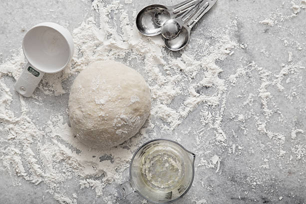 Pizza or Bread Dough Aerial View on Marble Pizza or bread dough on a floured marble countertop with measuring cup and spoons with copy space for text.  Please see my portfolio for other food and drink images.  flour mess stock pictures, royalty-free photos & images
