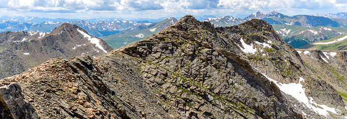A panoramic spring view of rugged west ridge of Mount Evan, humble Mount Bierstadt, and rolling high peaks of Front Range of Rocky Mountains, seen from summit of Mount Evan. Colorado, USA. 