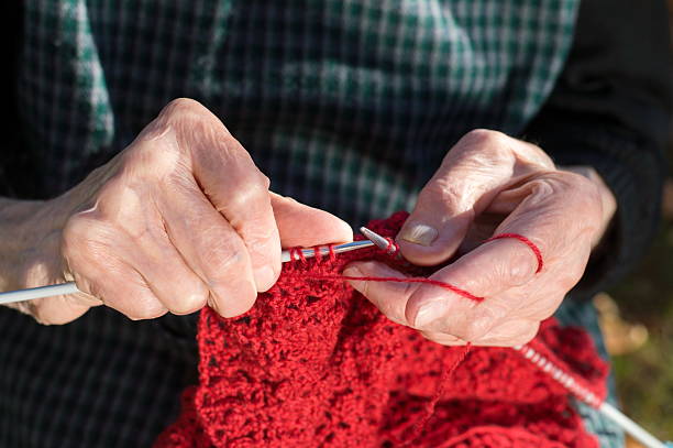 istock Senior woman hands knitting with red wool 598221484
