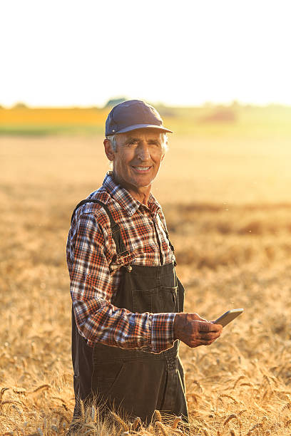 farmer using smart phone on field - onesie imagens e fotografias de stock