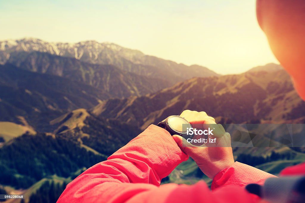 young woman hiker checking the altimeter on sports watch young woman hiker checking the altimeter on sports watch at mountain peak Mountain Stock Photo