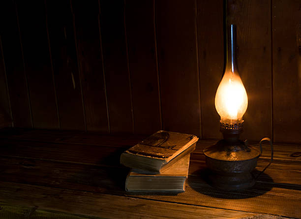 Old antique books with burning paraffin lamp. Old antique books with burning paraffin lamp near on the wooden table. old oil lamp stock pictures, royalty-free photos & images
