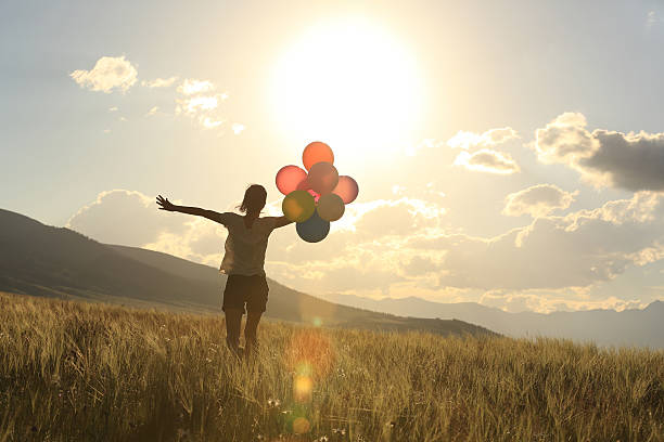 istock cheering young asian woman on grassland with colored balloons 598232004