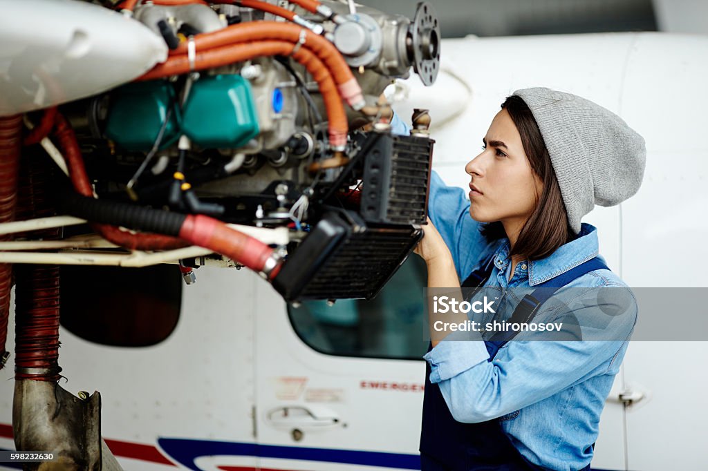 Repairing airplane motor Young woman in uniform fixing something in air jet motor Airplane Mechanic Stock Photo