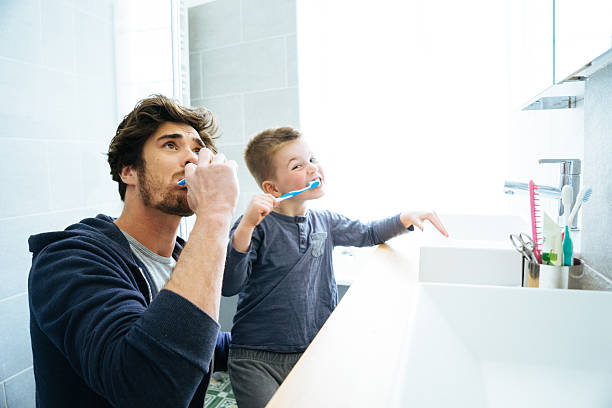 vater und sohn putzen ihre zähne - child brushing human teeth brushing teeth stock-fotos und bilder