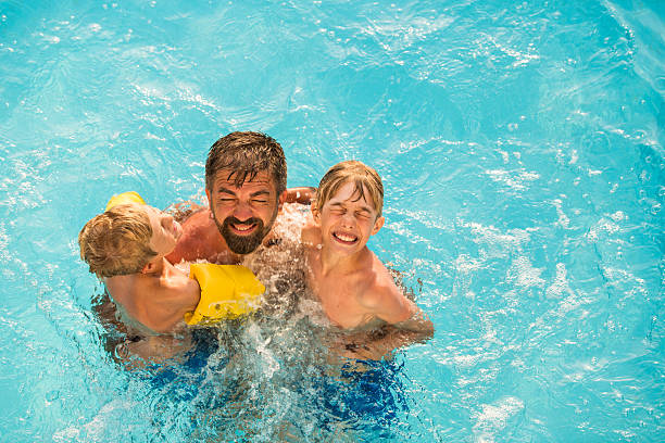 istock Dad with children in swimming pool 598234330