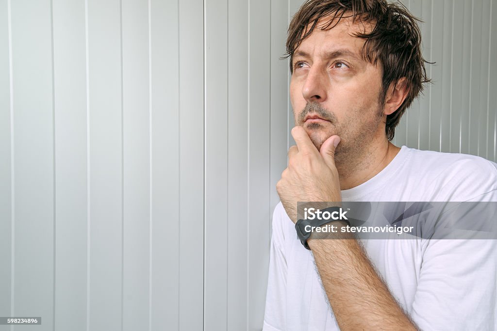 Man with hand on chin thinking deep thoughts Man with hand on chin thinking deep thoughts and making tough decisions Adult Stock Photo