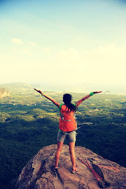 istock cheering successful woman hiker open arms at mountain peak 598237244