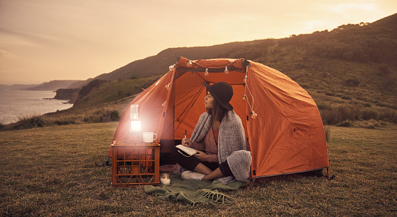 Shot of a young female camper sitting at her camp site