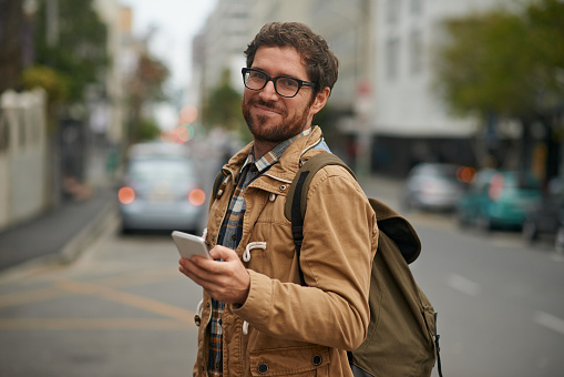 Portrait of a young man holding a mobile phone while out and about in the city