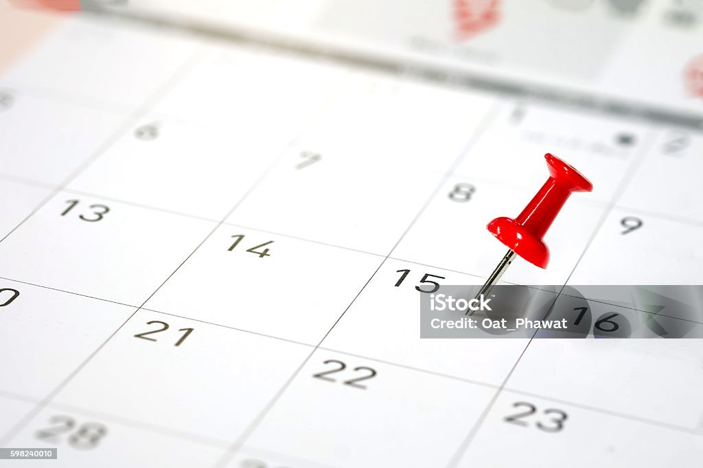 Embroidered red pins on a calendar Embroidered red pins on a calendar on the 15th with selective focus Calendar Stock Photo