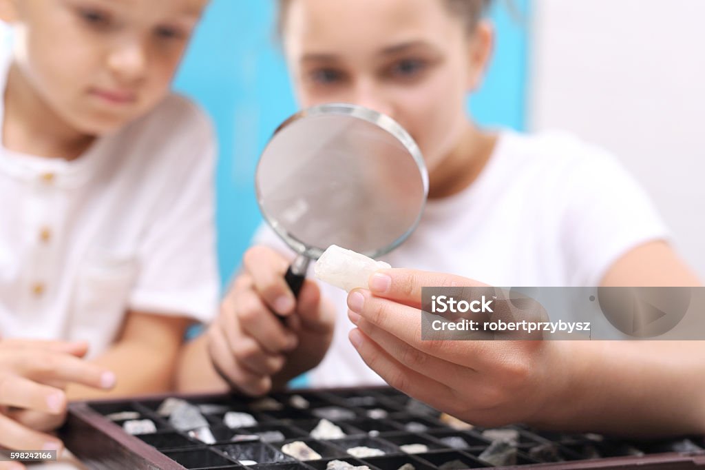 Geology collection of stones and minerals. Mineral. Two children, a girl and a boy watching through a magnifying glass stones from his collection of rocks. Collection Stock Photo