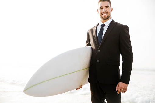 A Businessman holding is surfboard after a long day of work