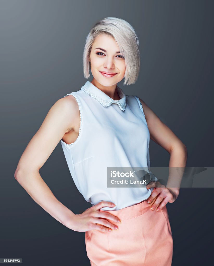 confident smiling woman confident smiling young woman against grey studio background Short Hair Stock Photo