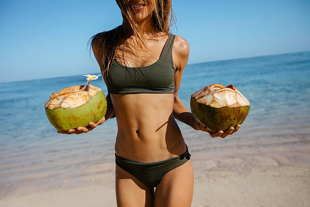 istock Woman in bikini on the beach with fresh coconuts 598245928