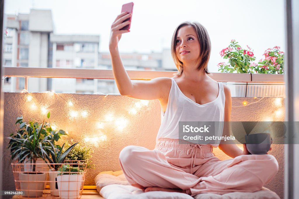 Selfie moment on terrace Women enjoy her special moment on terrace. She using her smartphone and taking selfie. Balcony Stock Photo