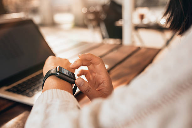 Young woman using smartwatch at a cafe Close up of young woman using smartwatch at a cafe. Female sitting at a table and checking her smart watch. checking the time stock pictures, royalty-free photos & images