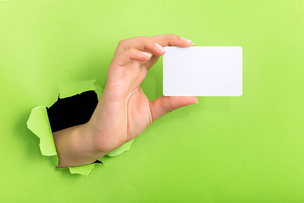 istock Female hand reaching through torn green paper sheet 598248332