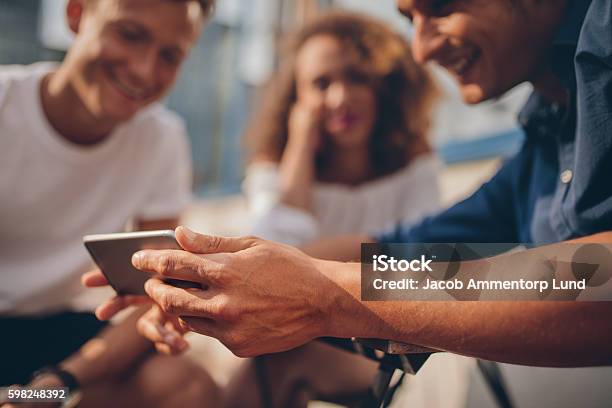 Junge Freunde Sitzen Im Freien Und Schauen Aufs Smartphone Stockfoto und mehr Bilder von Smartphone