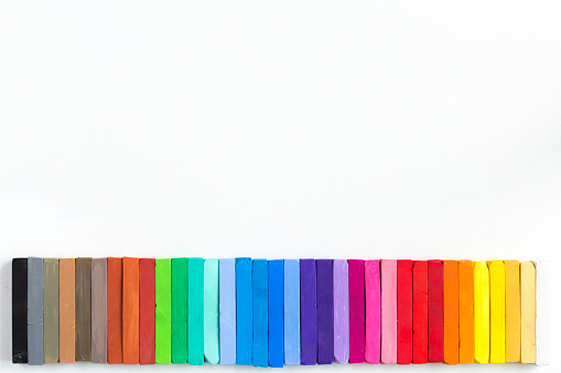 Top view of various kinds of multicolored school supplies like scissors, crayons, rulers, pencils, papers, markers, calculators, magnifying glass, clips, thumbtacks, sharpeners and brushes standing at the borders of the image on a frame shape  with copy space at the center of the image on a white background. Studio shot taken with Canon EOS 6D Mark II and Canon EF 24-105 mm f/4L