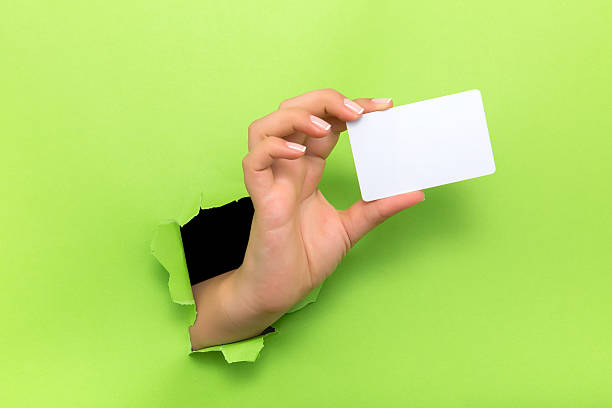 istock Female hand reaching through torn green paper sheet 598248600