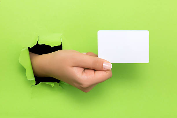 istock Female hand reaching through torn green paper sheet 598249932