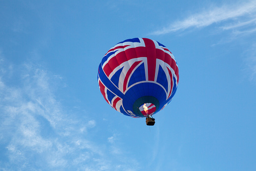 White military balloon in a blue sky with white clouds