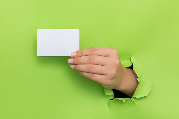 istock Female hand reaching through torn green paper sheet 598250134