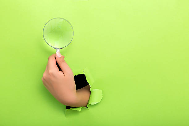 istock Large magnifying glass in hand isolated on green background 598252322