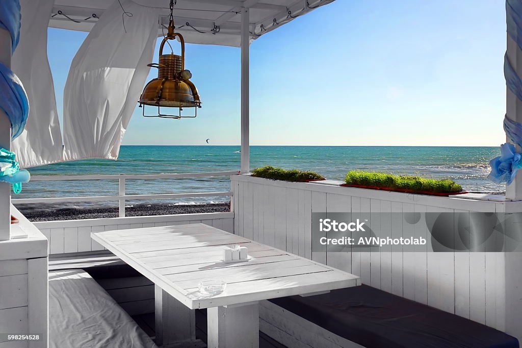Seaview Restaurant Interior. White Terrace With Wooden Furniture Seaview Restaurant Interior. White Terrace Or Veranda With Separated Cabins Under Tent And White Curtains. Wooden Furniture.  Hanging Lanterns. Porch Stock Photo