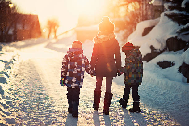 bracia i siostra chodzący po drodze w słoneczny zimowy wieczór. - winter family child snow zdjęcia i obrazy z banku zdjęć