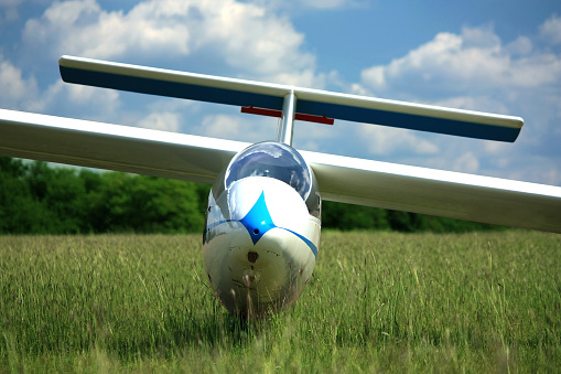 Blue white glider plane on airport grass